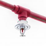 Fire sprinkler and red pipe on white ceiling background